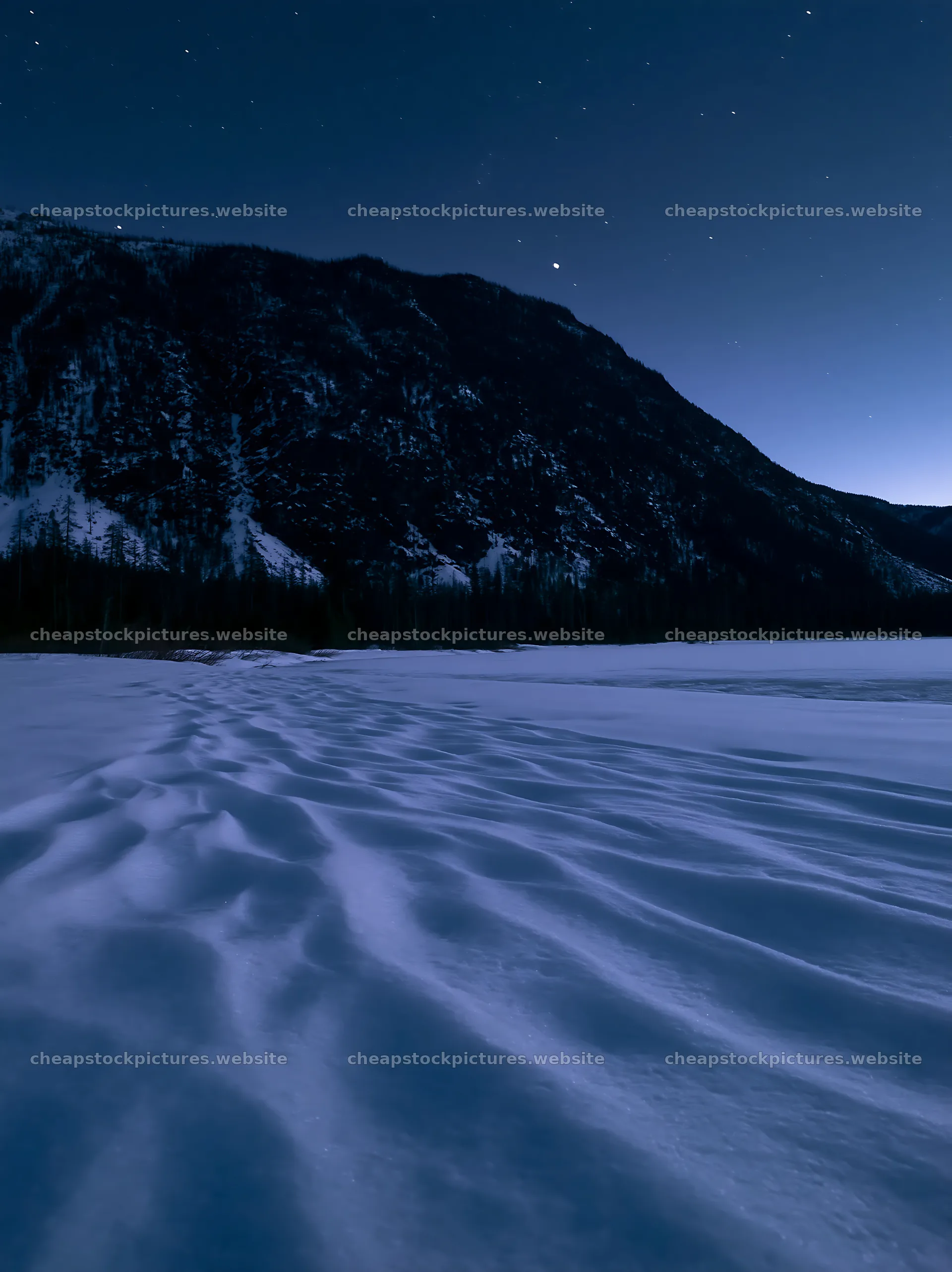 Snowy lakeside meadow at dusk under a mountain backdrop – stock pictures 6866x9174