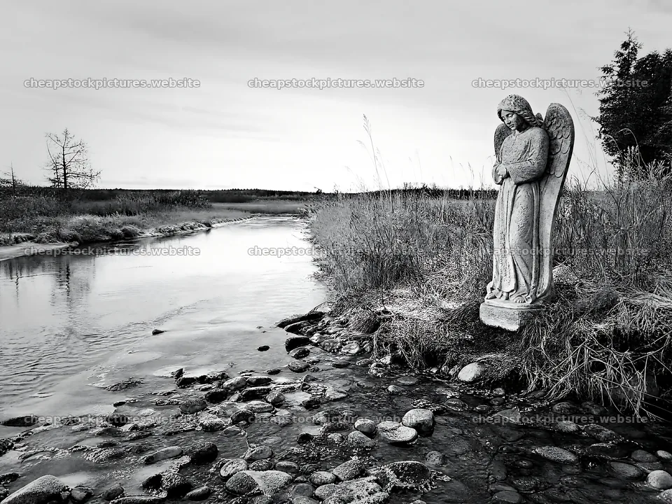 Winter angel statue by the river in a meadow landscape – stock pictures 9166x6874