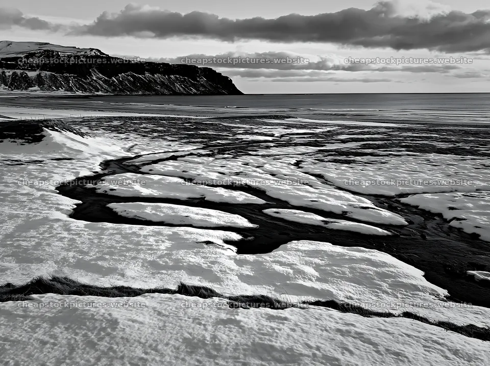 Snowbound meadow with flowing stream and cliffs in background – stock pictures 9174x6866