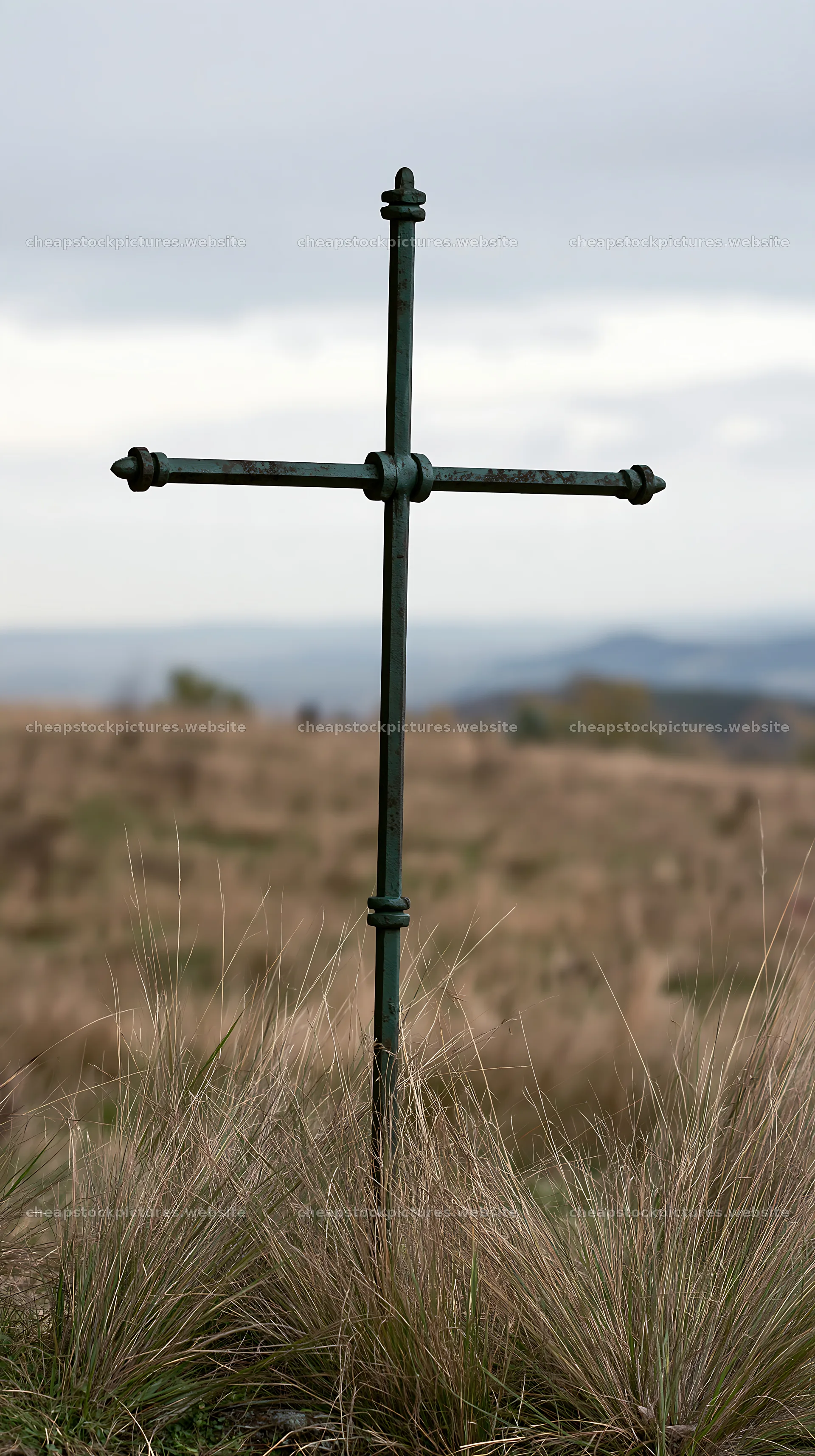 Iron Christian cross overlooking valley meadow in countryside – stock pictures 5938x10608