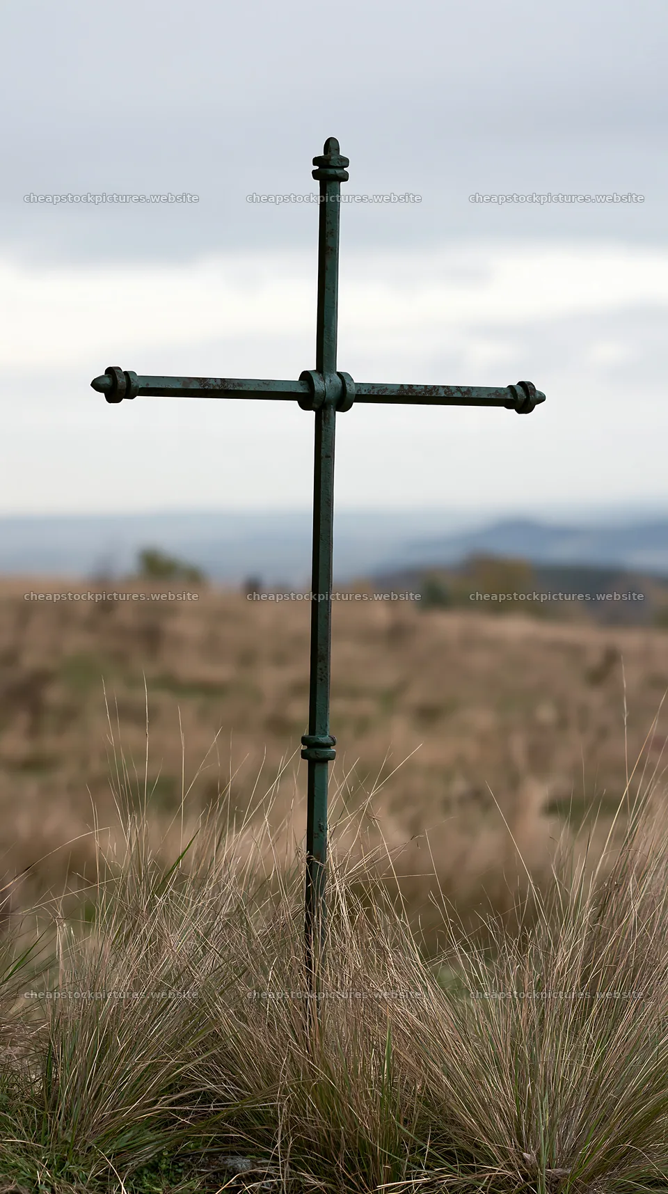 Iron Christian cross overlooking valley meadow in countryside – stock pictures 5938x10608