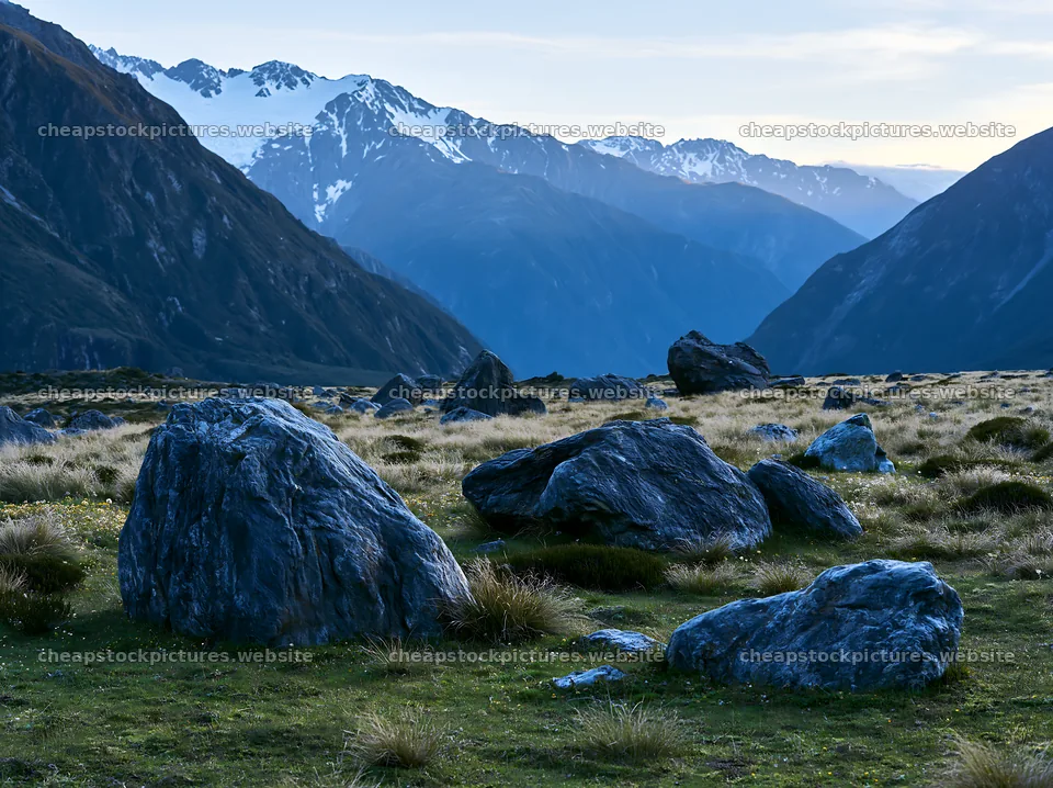 Boulders in a meadow with mountains in the background – stock pictures 9174x6866