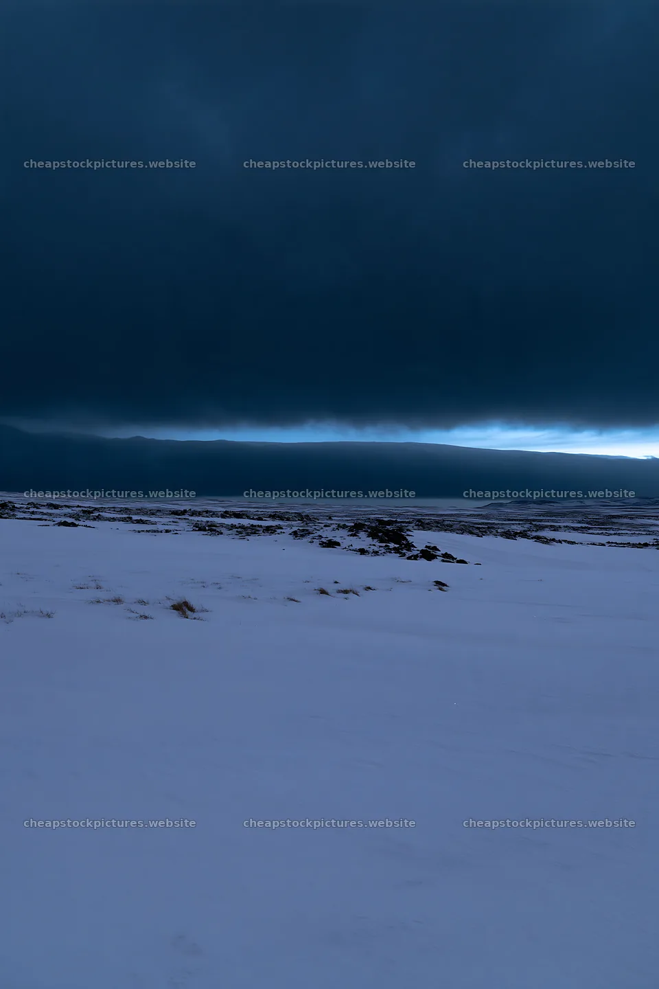 Snowbound meadow under dark clouds during twilight – stock pictures 6480x9722