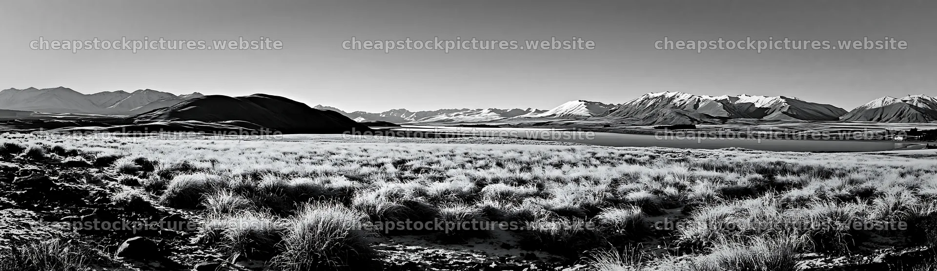 Lakeside meadow covered in snow with mountains in the background – stock pictures 14762x4268